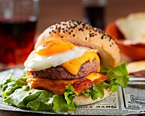 Burger of white bread, egg, cheese, salad, bacon and meat patty
